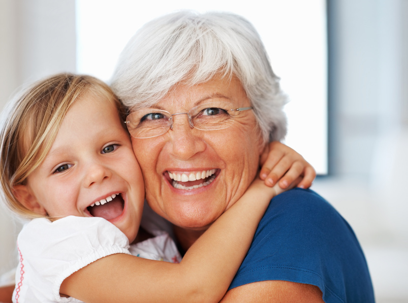 Closeup portrait of senior Caucasian woman hugging cheerful little granddaughter